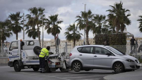 Una grúa municipal retira un vehículo de la vía pública.