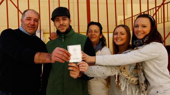 Samuel, con gorra, mostrando el boleto premiado con un décimo del Segundo Premio, junto a sus padres, hermana y amigos.