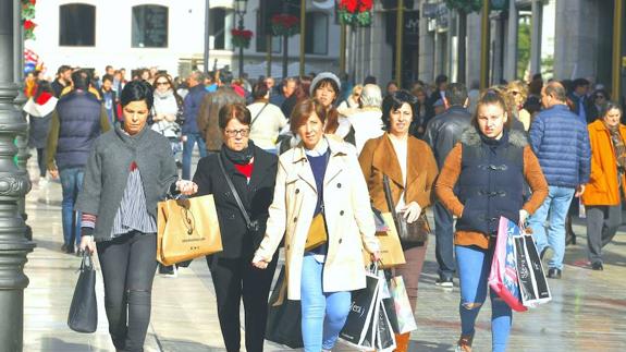 Varias personas pasean por la calle Larios ayer cargadas de bolsas.