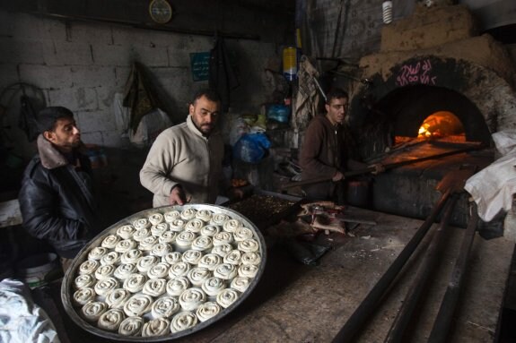 Varios palestinos se reúnen en una panadería de Gaza para cocinar sus alimentos. ::  MAHMUD HAMS / afp