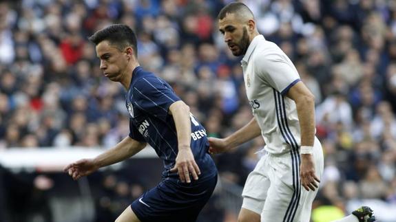 Juanpi avanza con el balón perseguido por Benzema. 