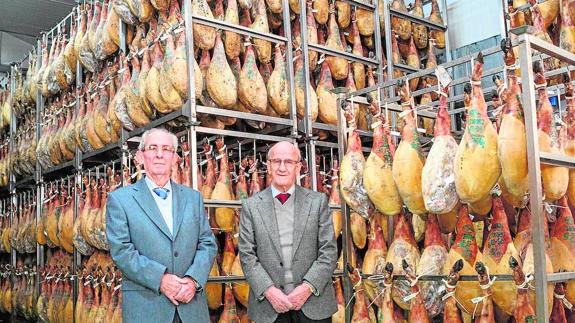 Anselmo Benito y su hermano Jesús, fundadores de la empresa, en el secadero de jamones de Arahal