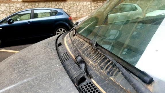 Arena acumulada en el capó de un coche en la capital.
