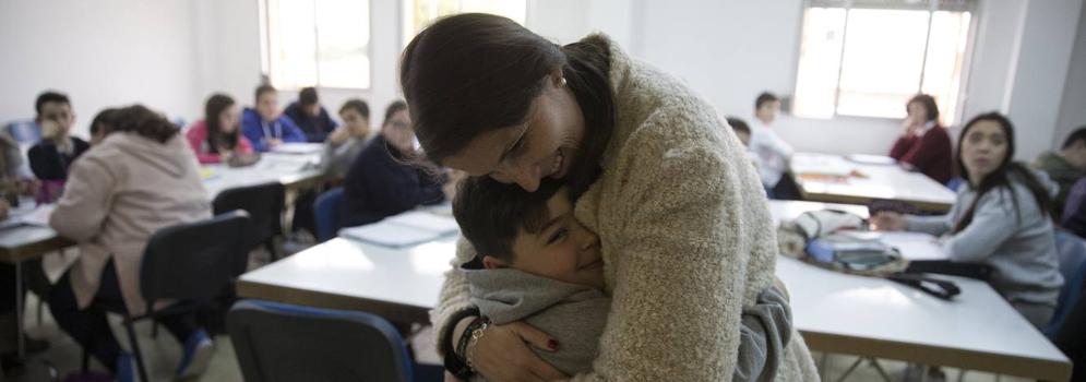 Nena y Brian se abrazan en el interior de un aula en la que estudian decenas de alumnos . 