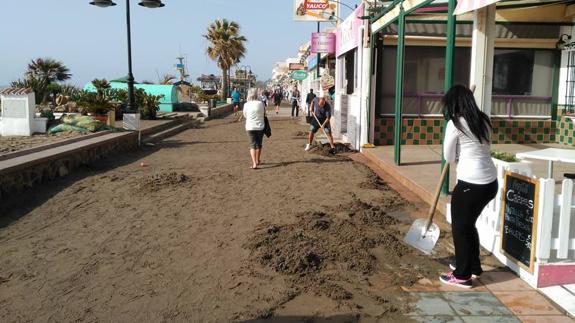 Con palas retiran la arena que el temporal ha depositado en el paseo marítimo en Torremolinos. 