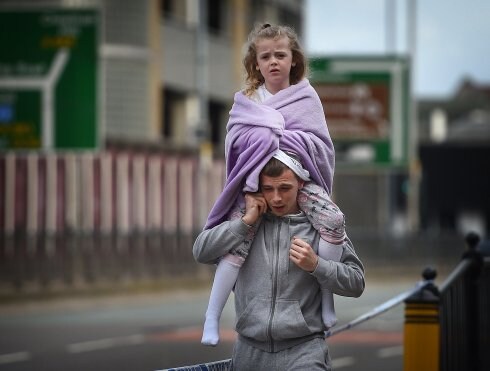 Un hombre lleva a hombros a una niña que se tapa con una manta, cerca de la estación Victoria y el lugar del atentado. ::  O. S. / AFP