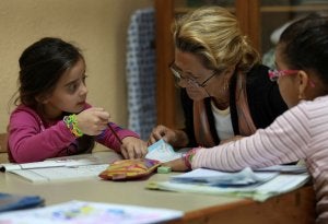 Una voluntaria ayuda a una niña con los deberes de clase. ::                             Á. CABRERA