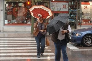 Una mujer sostiene con fuerza el paraguas para que no se vuele con la fuerza del viento. ::
JOSELE-LANZA