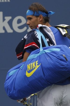 Rafa Nadal abandona la pista con su bolsa de raquetas. ::
AP