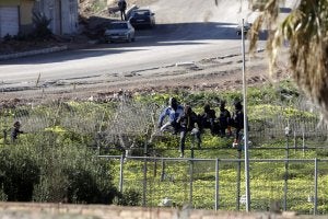 Varios inmigrantes, encaramados a la valla el pasado domingo. ::
FRANCISCO G. GUERRERO. EFE