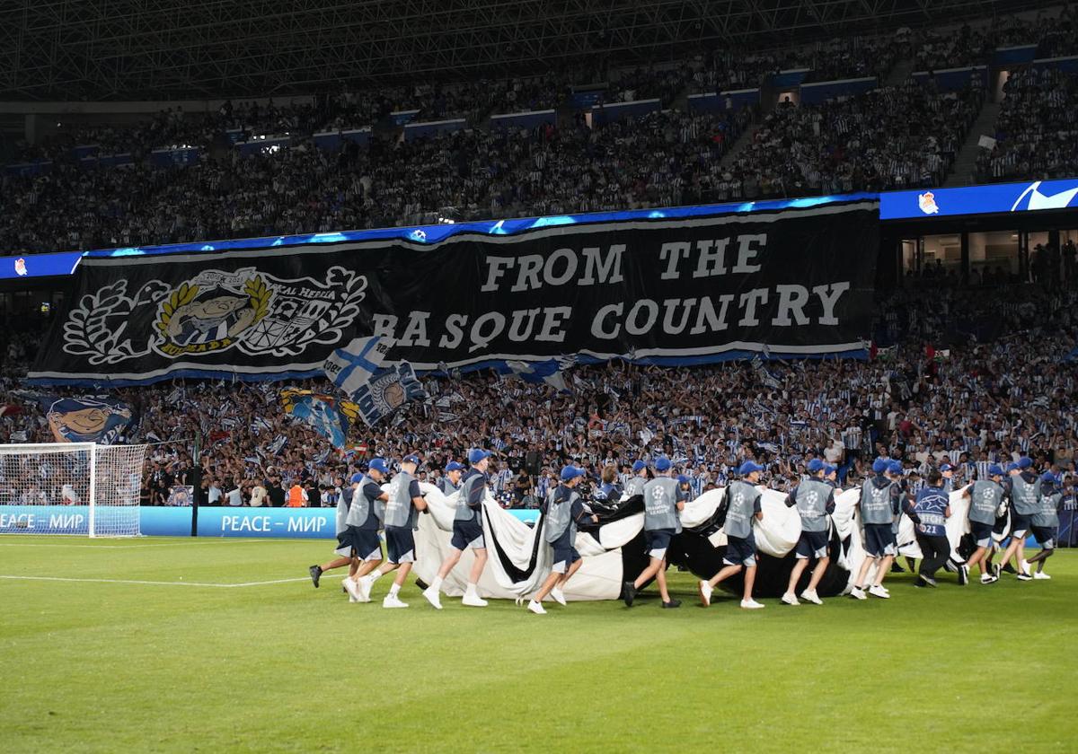 Los operario retiran la lona de la Champions poco antes de comenzar el partido.