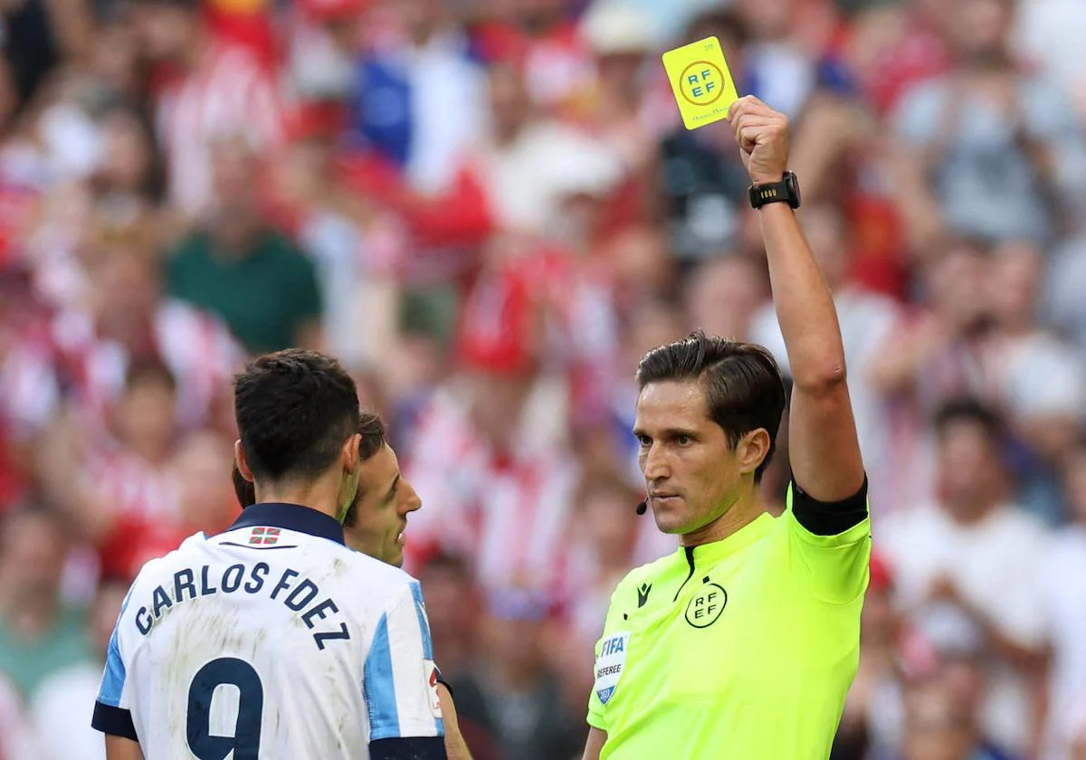 Munuera Montero muestra la tarjeta amarilla a Carlos Fernández por la mano que cometió en el partido entre el Atlético de Madrid y la Real Sociedad.