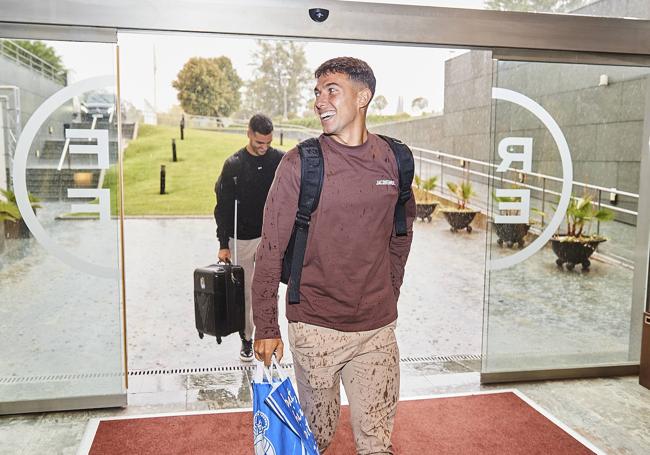 Martin Zubimendi, llegando empapado pero sonriente a una convocatoria anterior de la selección española, con su bolsa txuri-urdin.