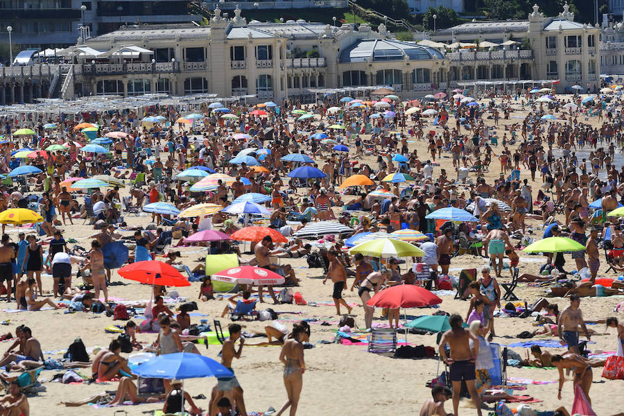 El fuerte calor ha hecho que las playas guipuzcoanas presenten este lunes una masiva alfuencia de gente. En las imágenes, San Sebastián y Zarautz.