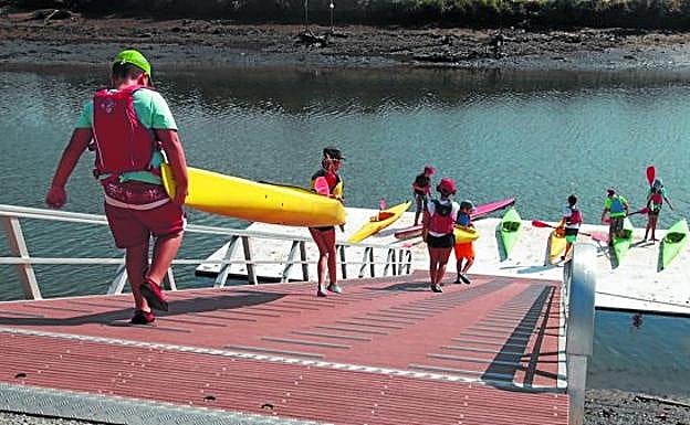 Piragüismo. Los niños de Uda de la Sociedad Deportiva Santiagotarrak bajando las piraguas al muelle del río Bidasoa.