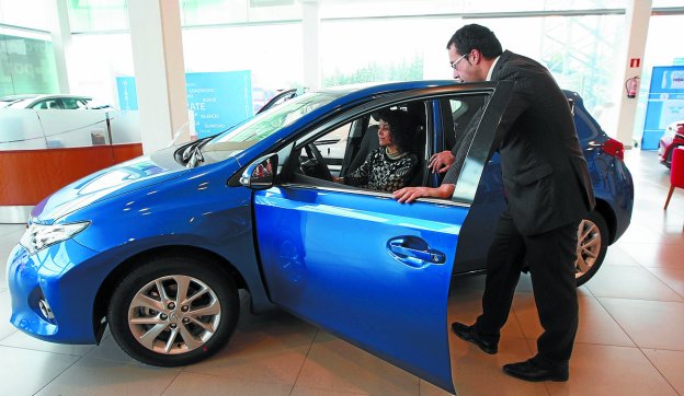 Un vendedor muestra las características de un vehículo a una clienta.