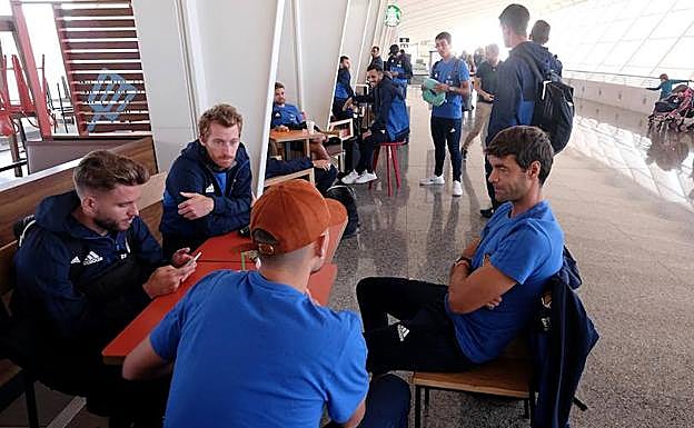 Imagen principal - Los jugadores esperan la salida del chárter en Loiu, guardan sus pertenencias antes de despegar, y Jokin Aperribay a la llegada a San Petersburgo.