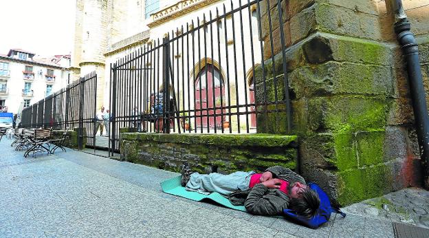 Un hombre duerme durante el día junto a la iglesia San Vicente en Donostia. 