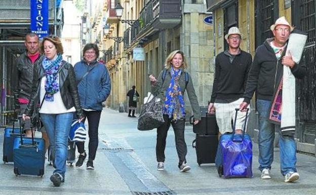 Turistas pasean por la Parte Vieja de Donostia portando las maletas preparadas para alojarse en la capital guipuzcoana. 