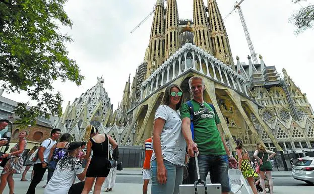 Varios turistas se fotografían junto a la Sagrada Familia en Barcelona.