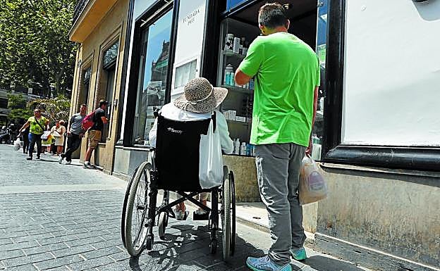 Un hombre acompaña a una mujer dependiente por las calles de Donostia.