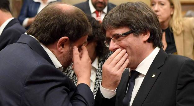 El gesto. Carles Puigdemont y Oriol Junqueras dialogan tapándose la boca para que nadie pueda leer sus labios.
