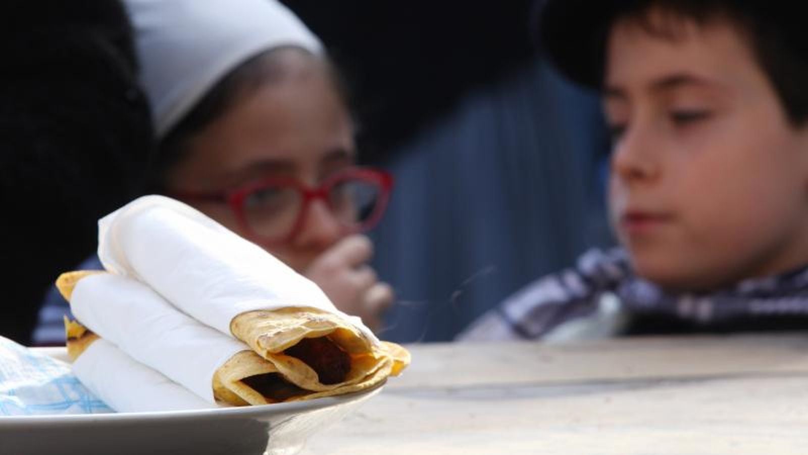 Mayores y niños disfrutan de los talos y la txistorra que se ofrecen en lo diferentes puestos de la localidad