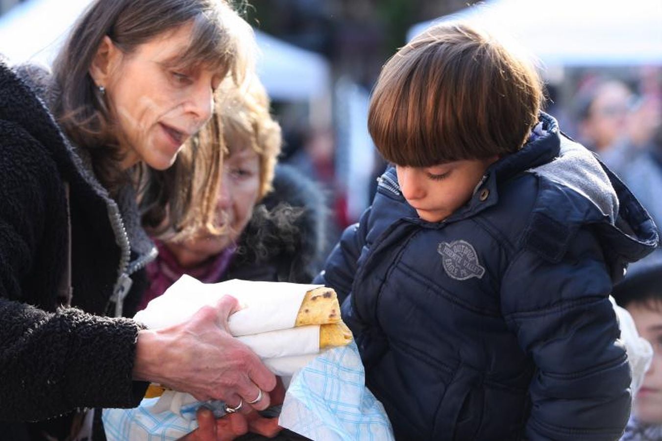 Mayores y niños disfrutan de los talos y la txistorra que se ofrecen en lo diferentes puestos de la localidad