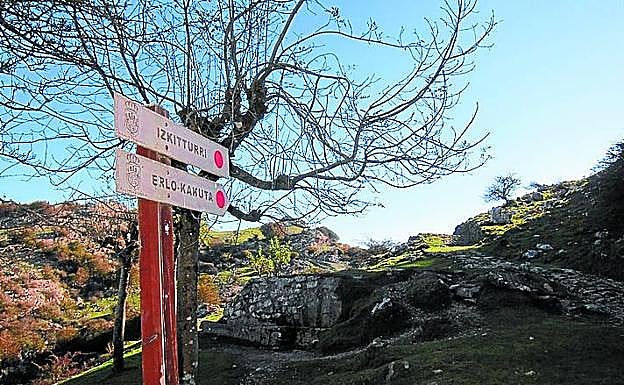 Imagen principal - En la imagen superior, Fuente de Izki de camino al Erlo señalizado.. Debajo a la izquierda, enorme estatua de San Ignacio sobre su santuario. A su derecha, espectaculares vistas desde los alredores de Izarraitz. 
