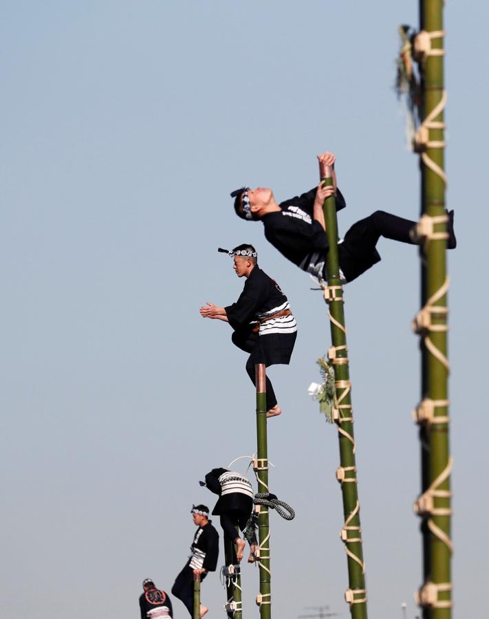 Los miembros de la Asociación de Preservación de Edo Firemanship muestran sus habilidades de equilibrio sobre escaleras de bambú durante la revisión de Fuego de Año Nuevo del Departamento de Bomberos de Tokio