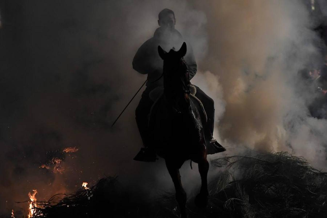 Varios jinetes salta sobre una hoguera en el pueblo de San Bartolomé de Pinares en la provincia de Ávila durante la inauguración de la tradicional fiesta religiosa 'Luminarias' en honor a San Antonio Abad.