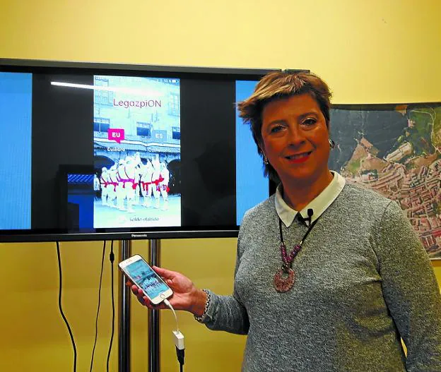 La alcaldesa mostrando la portada de la nueva aplicación, protagonizada por la Ezpata Dantza.