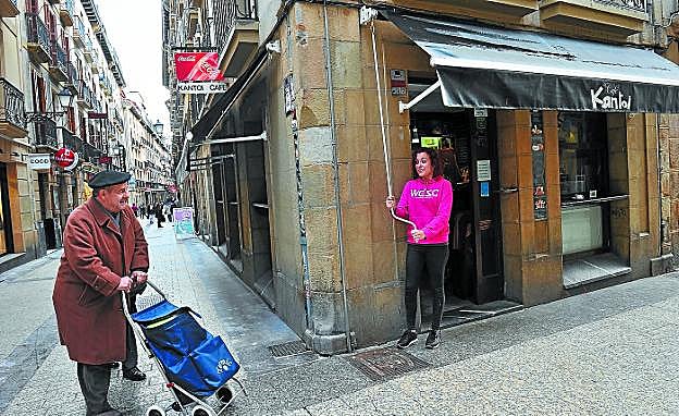 Iris Cejudo, propietaria del café Kantoi, abre el toldo de su establecimiento, que el Ayuntamiento ha ordenado retirar de la fachada.