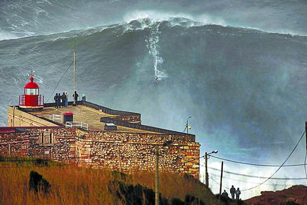 Un surfista desciende una inmensa pared de agua en Nazaré. El público llenará hoy los acantilados próximos para seguir la prueba. 