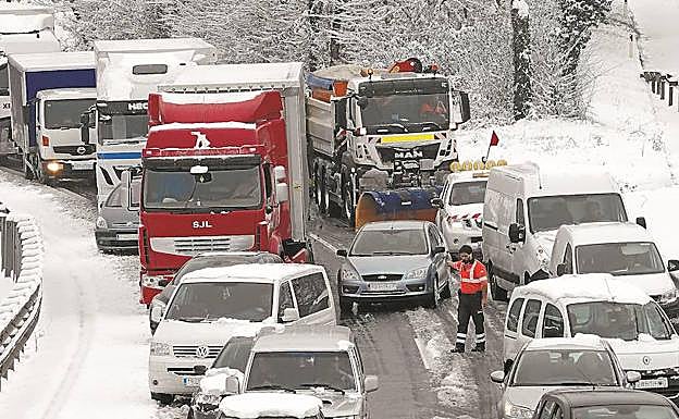 Un quitanieves intenta abrirse paso, a la derecha de la imagen, entre el atasco de coches y camiones en la N-1 a la altura de Lasarte-Oria.