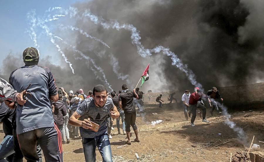 Manifestantes corren para protegerse del gas lacrimógeno lanzado por soldados israelíes durante unas protestas en la frontera de Gaza.