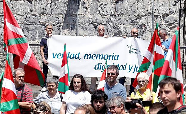 Al fondo, miembros de la Asociación de Víctimas del Terrorismo durante su protesta en el acto.
