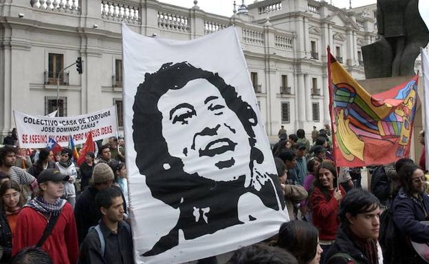 Manifestantes portan un cartel con la imagen del cantautor chileno Víctor Jara. 