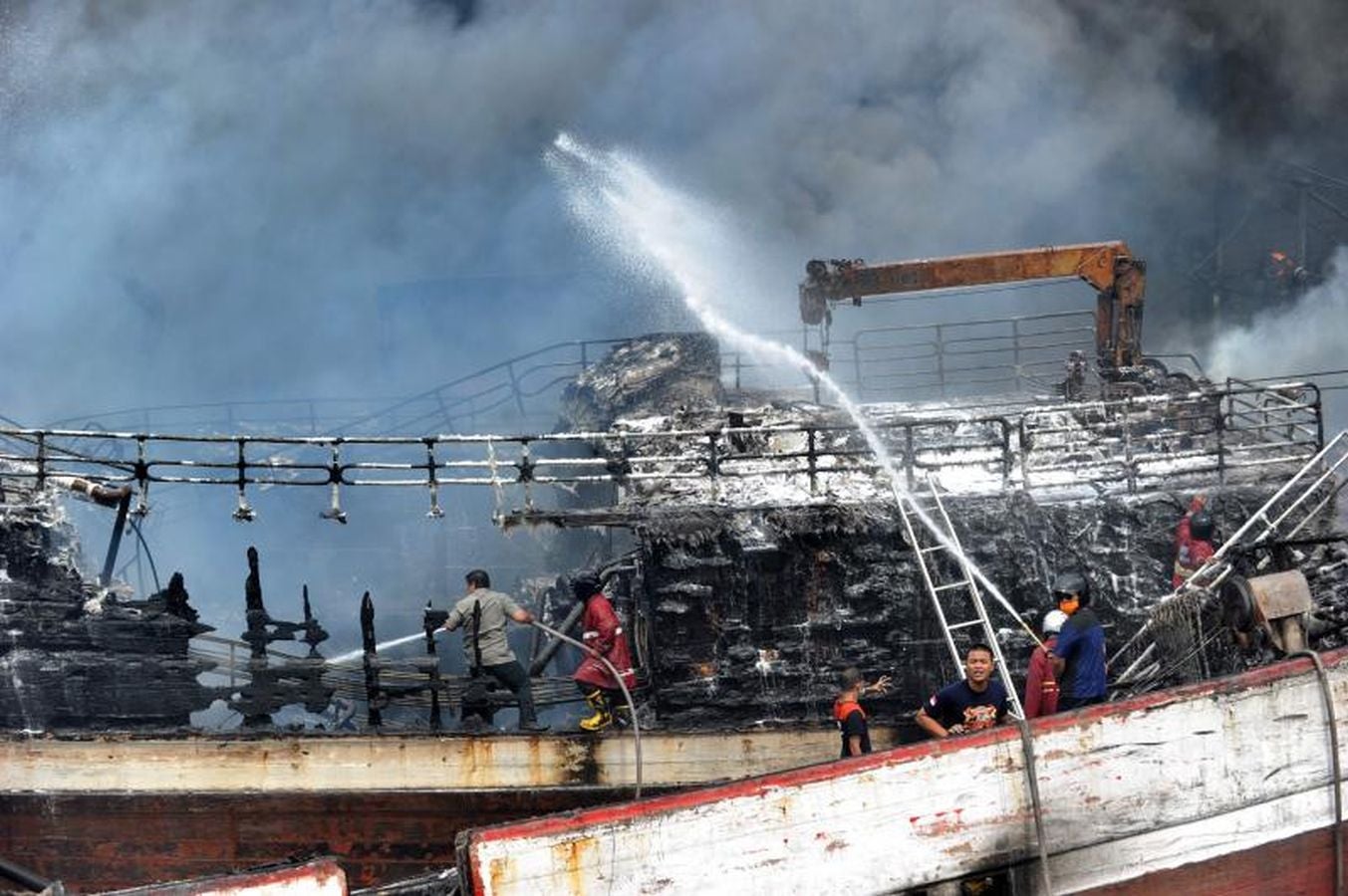 Varios bomberos trabajan en la extinción de un incendio de un barco en el puerto de Benoa, en Bali (Indonesia).