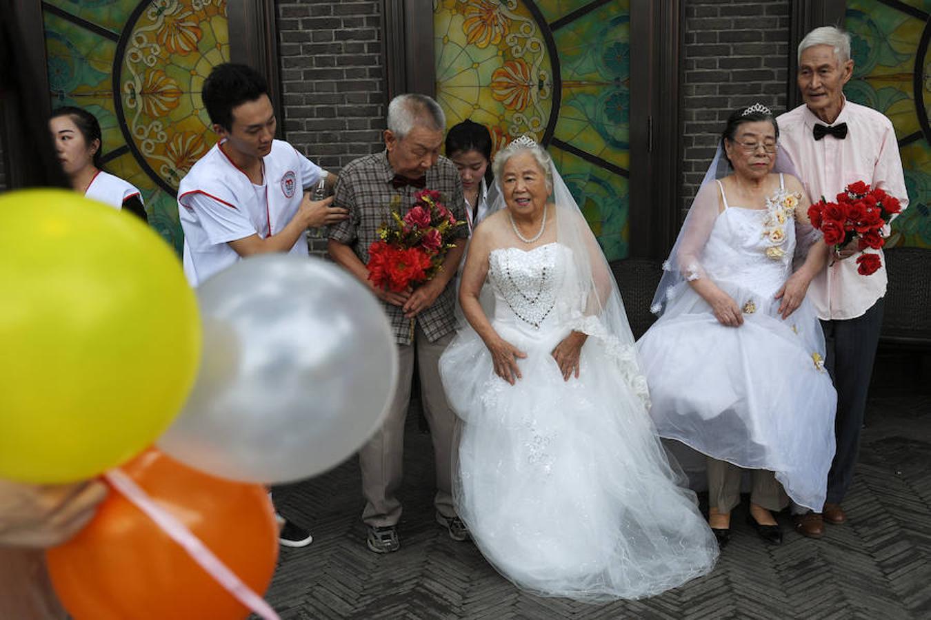Parejas mayores que lleven más de 50 años casadas posan durante un evento para recrear las fotos de boda por el festival Qixi, el San Valentín chino, en Tianjin.