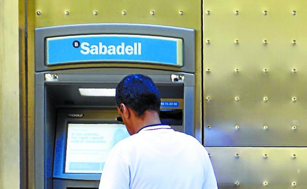 Un hombre utiliza un cajero del Banco Sabadell en Barcelona. 
