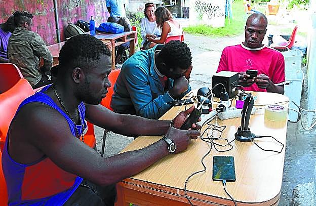 Migrantes cargando el móvil en el gaztetxe de Lakaxita, en Irun.
