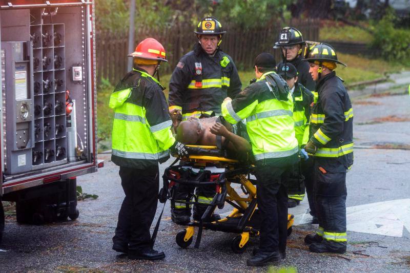 Trabajadores de los equipos de rescate trasladan a un hombre herido tras la caída de un árbol en su vivienda.