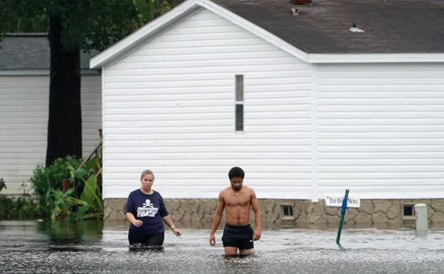 Dos personas caminando por una calle inundada en Piney Green.