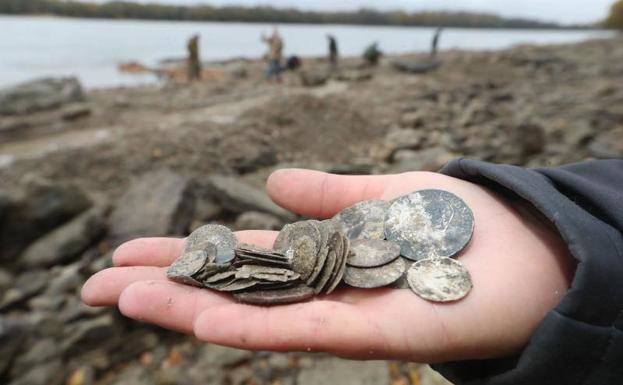 Un arqueólogo húngaro sostiene en su mano parte de las monedas halladas.