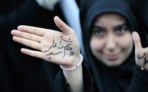 Una joven muestra un mensaje escrito en su mano que reza «estamos preparados para sacrificarnos por el Líder Supremo el Ayatola Ali Jameini» durante una manifestación convocada con motivo del aniversario de la toma de la Embajada de EE UU en Teherán.