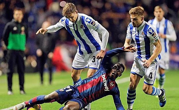 El delantero ghanés del Levante, Emmanuel Boateng, cae ante la entrada de los jugadores de la Real Sociedad, Diego Llorente y Asier Illarramendi 