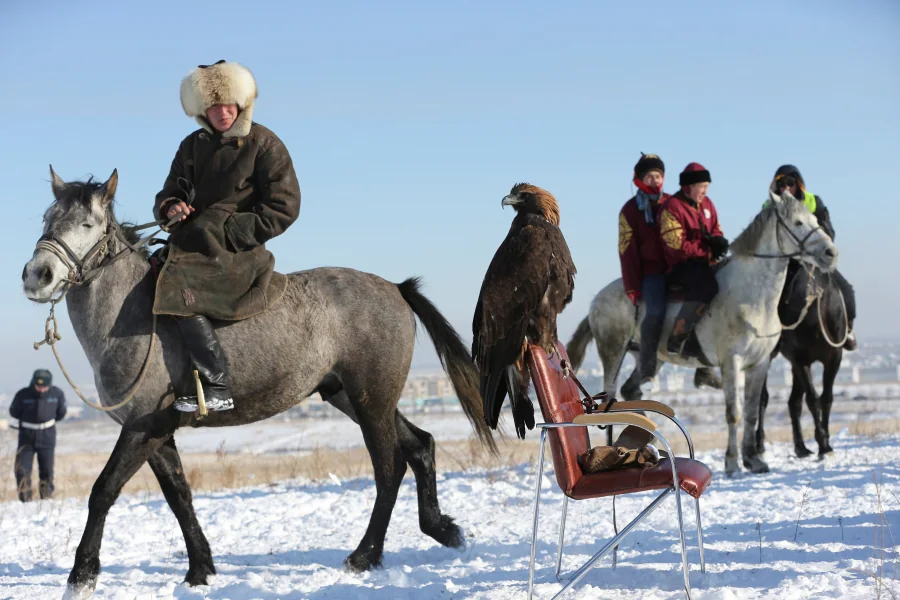 Los participantes del concurso de caza tradicional con cetrería en Almaty, Kazajistán, esperan su turno, con sus aves, bajo el frío invernal de diciembre.