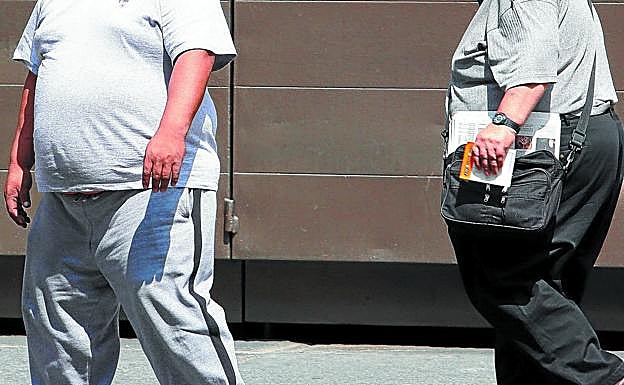 Dos hombres que padecen obesidad caminan por la calle.