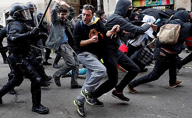 Policías persiguen a varios jóvenes durante las protestas. 